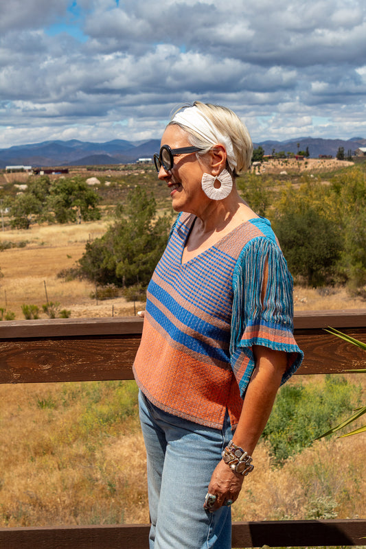 Blusa 100% algodón con textil artesanal tejido en telar de pedal. Cuello en V y mangas en deshilado amplio. Pieza única.