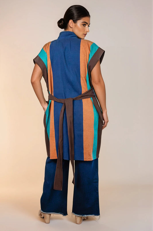 Chaleco multicolor con textil artesanal tejido en telar de pedal, abierto del frente con dos tiras integradas en los costados que funcionan como cinto. Bolsas ocultas en los costados. Visto de espalda.