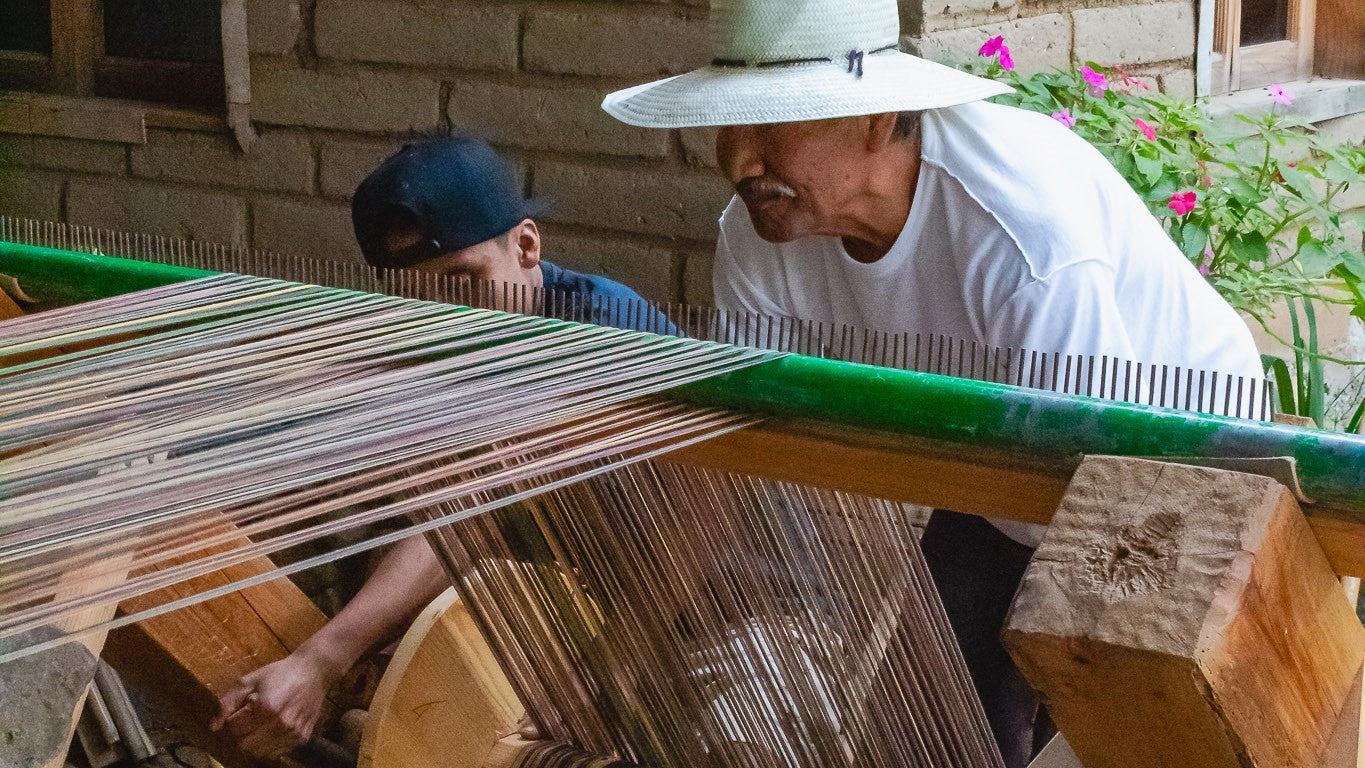 Toño y su papá, ambos maestros artesanos, preparan con cuidado hilo por hilo para que la base en el telar quede justamente en la combinación de colores como se desea.