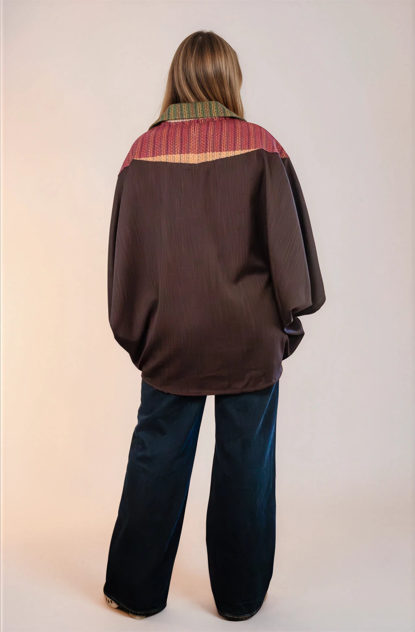 Poncho oversize unisex con cierre al frente y cuello camisero, con guinda en espalda alta. Vista de espalda.